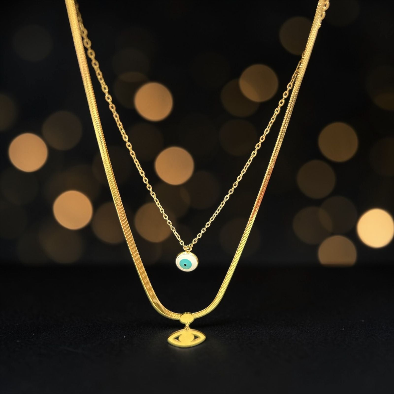 A gold snake back necklace with eye and white circle